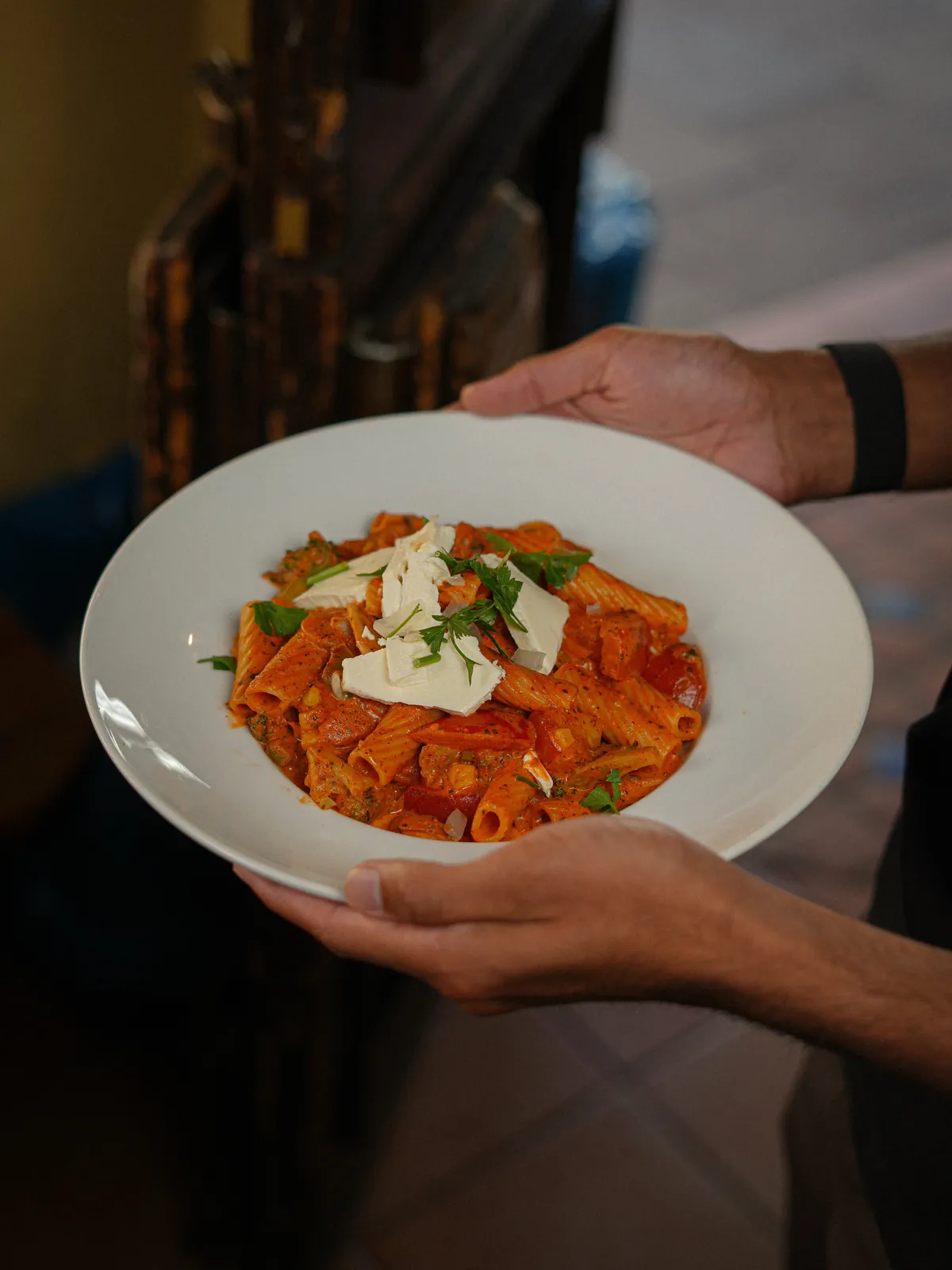 Rigatoni in Tomatensauce mit Hobelkäse und Kräutern, im Laden serviert